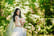 A bride posing for her wedding photos in a forest, holding her bouquet 