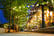 Decorated and illuminated sidewalk with a line of trees, at blue hour. Lights coming in from the bars and restaurants near Dambovita river, Bucharest