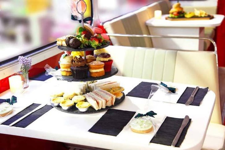 Afternoon tea food selection on a Vintage Bus, including sandwiches, tarts, cupcakes and macarons