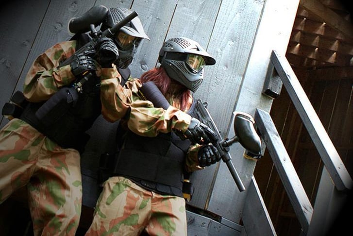 Two friends about to storm a hut whilst paintballing