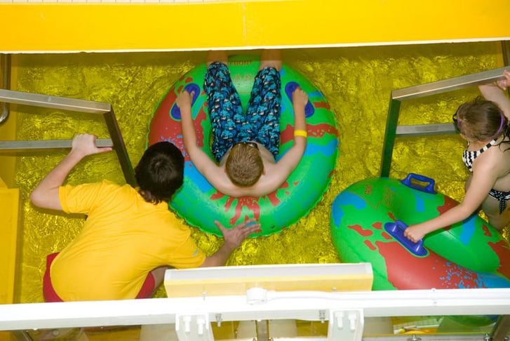 A kid about to go down a water slide on a rubber ring 