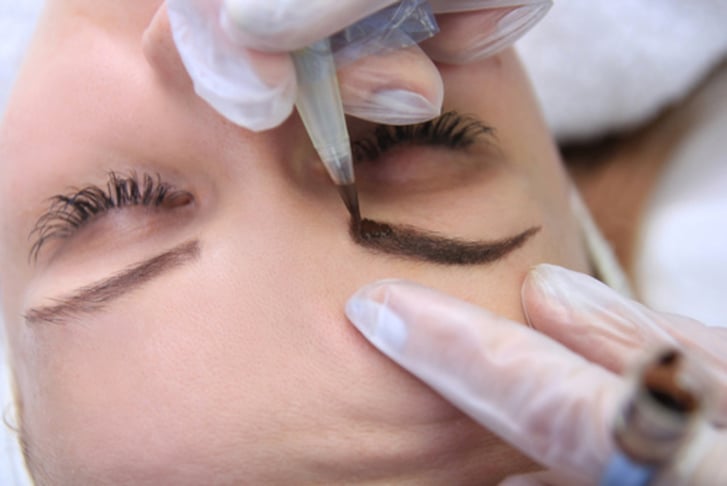 A woman receiving an eyebrow micro-blading treatment