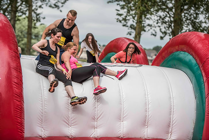 A group of runners sliding down an inflatable slide