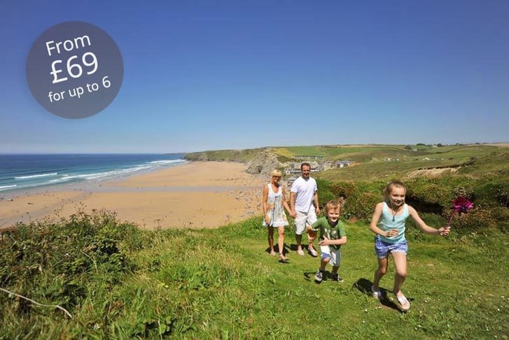 A family taking a walk along a cliff top over looking a beach