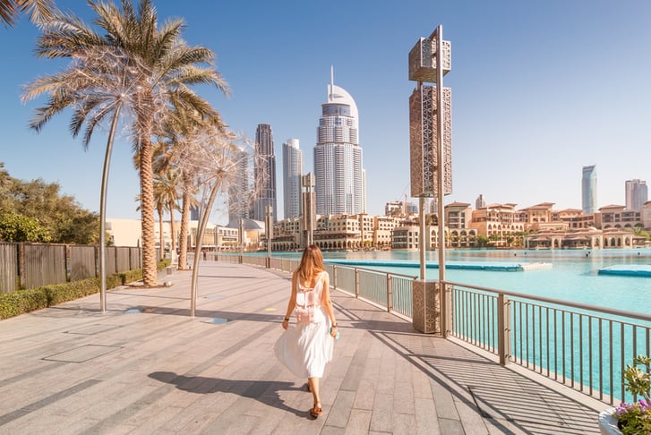 Happy tourist girl walking near fountains in Dubai city