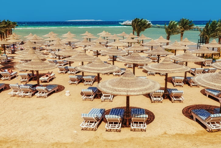 Chaise lounge and parasols on the beach against the blue sky and sea. Egypt, Hurghada