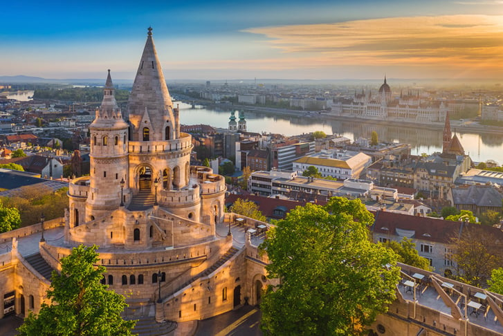 Budapest, Hungary - Beautiful golden summer sunrise with the tower of Fisherman's Bastion and green trees.