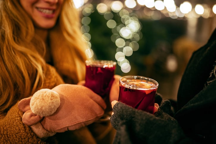 Close-up woman's hands in winter mittens with hot cup of hot mulled wine.