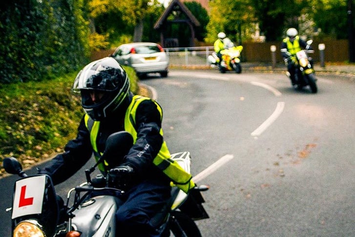 A learner motorcycle rider wearing a high-visibility jacket whilst out on their CBT