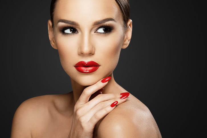 A woman with bright red lipstick and matching nails