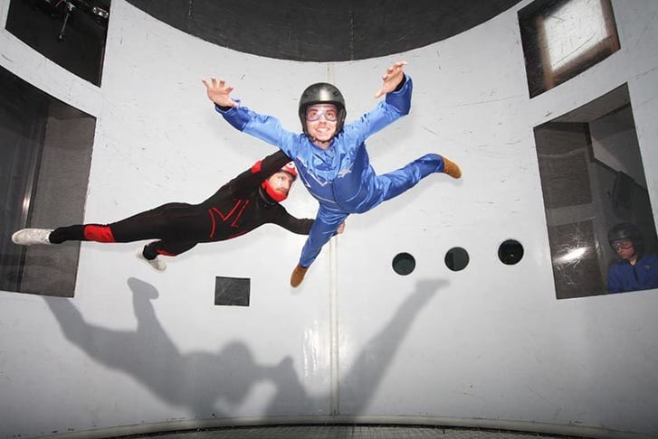 A man and an instructor in an indoor sky diving simulator