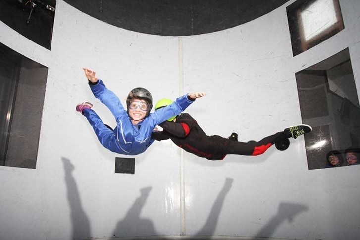 A woman and an instructor in an indoor skydiving simulation