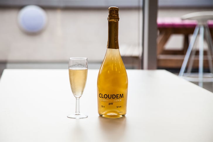 A bottle of Cloudem Sparkling Wine next to a glass of it poured out