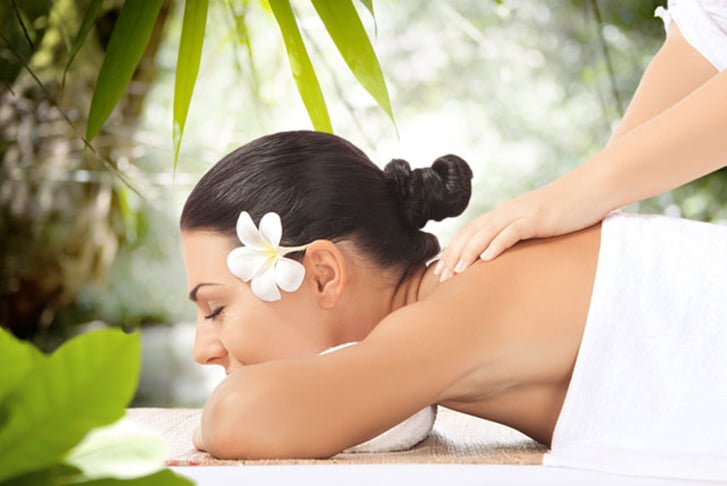 A woman with a flower in her hair having a massage
