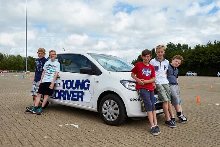 A group of kids stood around a young drivers car