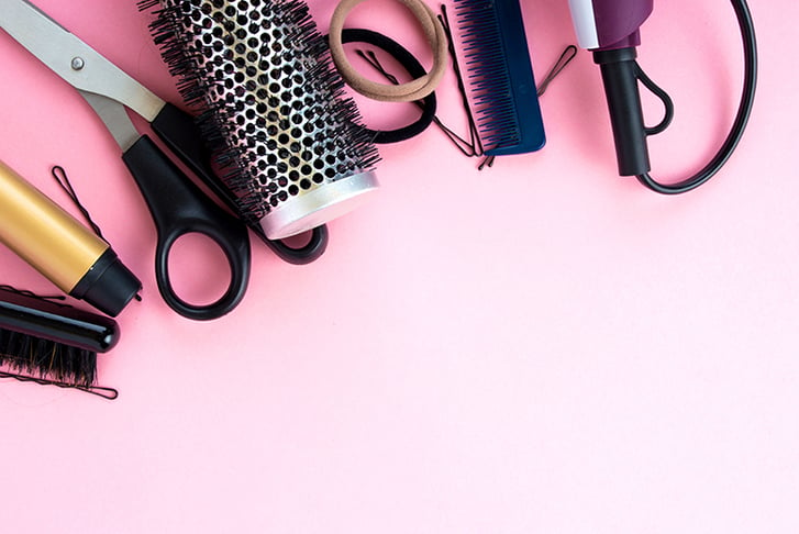 Scissors and other hairdressing tools on a pink background