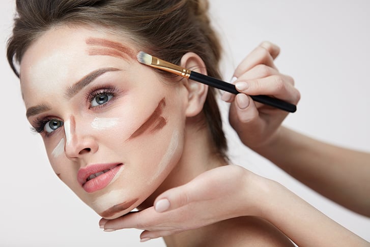 Makeup artist contouring a woman's cheek