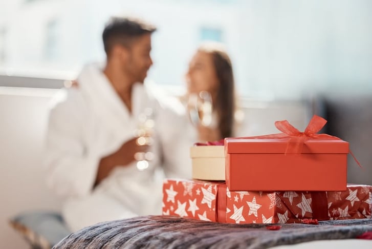 Christmas gift, present and happy couple celebrate the holiday at hotel with champagne.